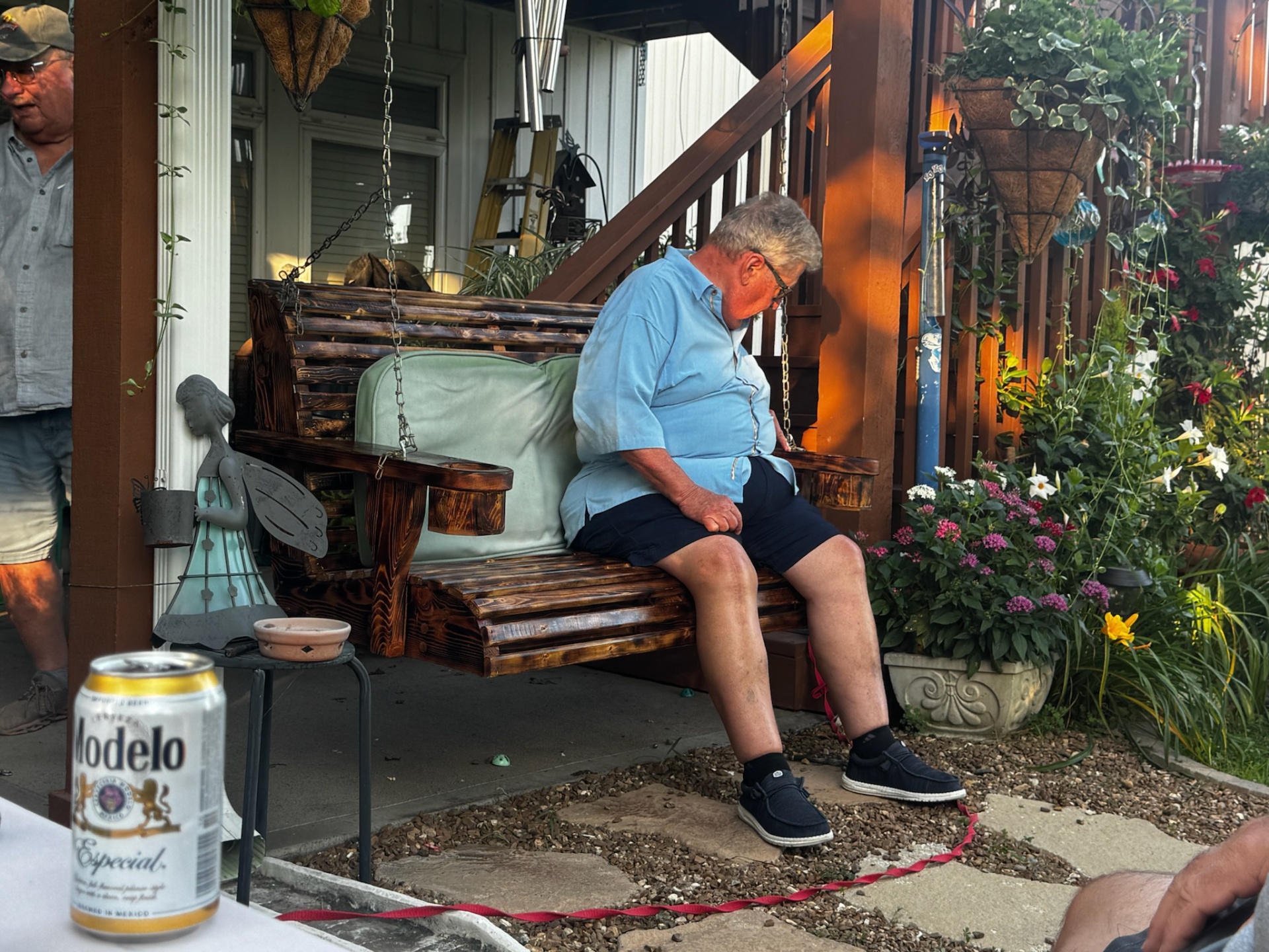Custom wooden porch swing with dark stain hanging from chain mount